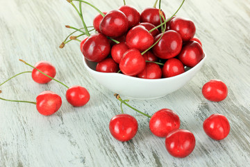 Cherry berries in bowl on wooden table close up