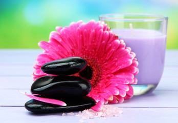 Spa stones, beautiful gerbera and candle on wooden table