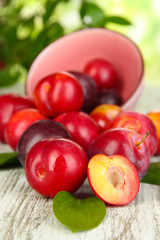 Ripe plums on wooden table on natural background