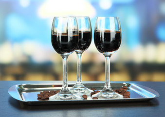 Glasses of liquor on tray,  on bright background