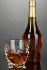Glass of whiskey with bottle, on dark background
