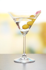 Martini with green olives on table in bar