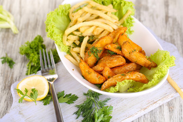 French fries and home potatoes on plate on board on wooden