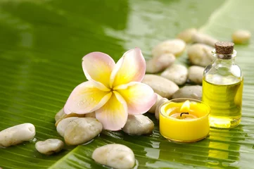 Rolgordijnen Massage oil and Plumeria flower and stones on green banana leaf © Mee Ting