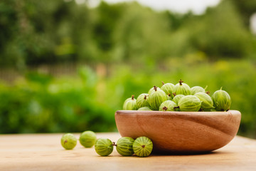 Close-Up Of Gooseberries In Vintage Wooden Bowl On Wooden Table