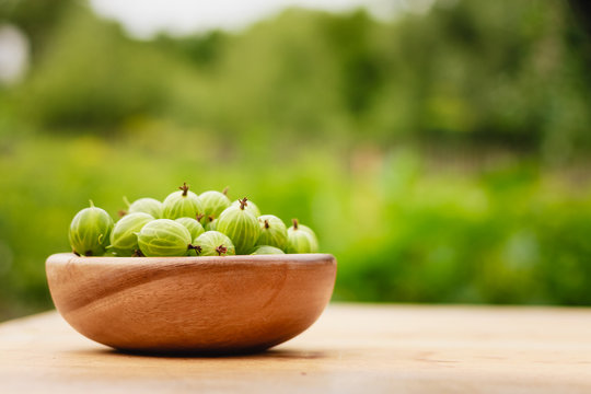 Close-Up Of Gooseberries In Vintage Wooden Bowl On Wooden Table