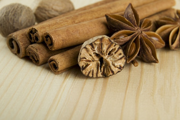 Cinnamon sticks, nutmeg and anise stars over wooden background