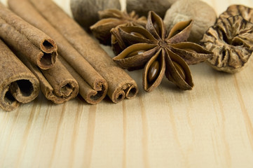 Cinnamon sticks, nutmeg and anise stars over wooden background