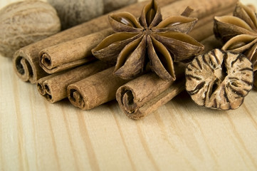 Cinnamon sticks, nutmeg and anise stars over wooden background