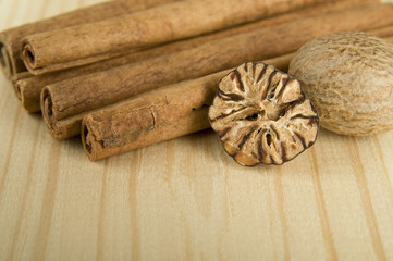 Cinnamon sticks and nutmeg over wooden background