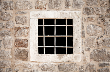 Ancient stone prison wall with metal window bars