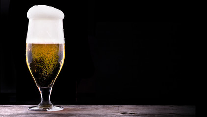 Frosty glass of light beer on black background