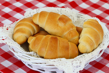 Butter croissants in bread basket on checkered tablecloth