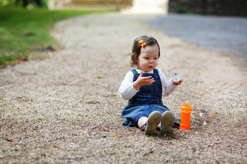 Little cute baby girl playing with soap bubbles in summer park