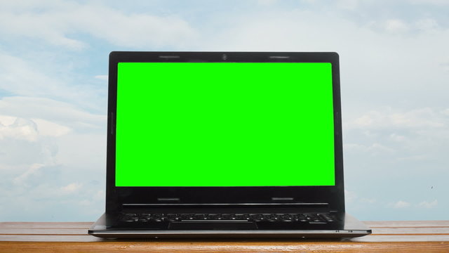 laptop with green screen on a background of the sky