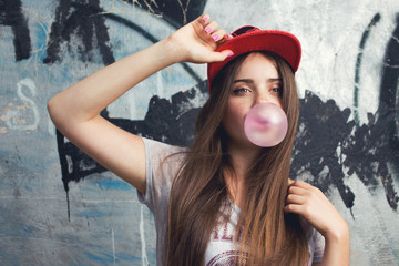 trendy model posing on graffiti. Blow bubblegum