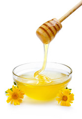 Sweet honey pouring from wooden dipper in glass bowl isolated