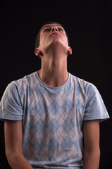 Serious and thoughtful teenage boy sits on chair, he thinks no o