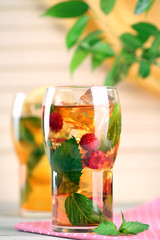 Iced tea with raspberries, lemon and mint on wooden table