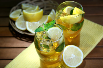 Iced tea with lemon and mint on wooden table