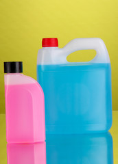 Blue and pink liquids for car in canisters on green background