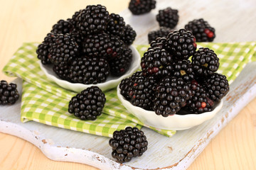Sweet blackberry in bowls on wooden table