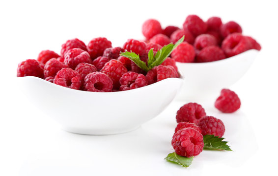 Ripe sweet raspberries in bowls, isolated on white
