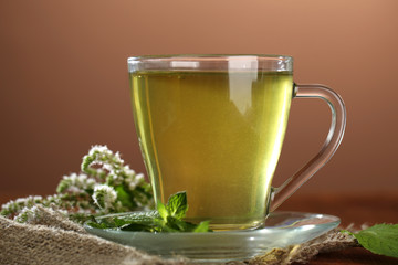 Cup of herbal tea with fresh mint flowers on wooden table