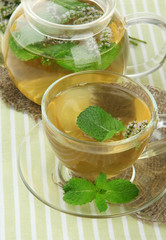 Teapot and cup of herbal tea with fresh mint flowers