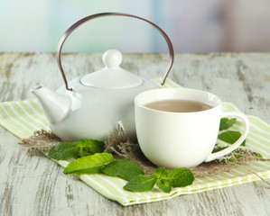 Teapot and cup of herbal tea with fresh mint flowers