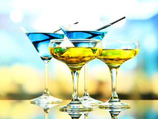 Glasses of cocktails on bright background