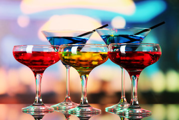 Glasses of cocktails on bright background