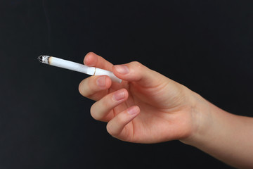Woman hand holding cigarette with smoke, isolated on black