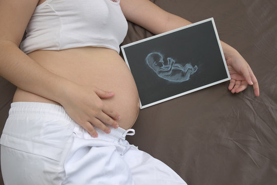 pregnant woman and baby drawing on blackboard
