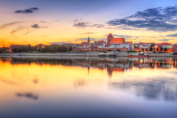 Fototapeta na wymiar Toruń Stare Miasto odzwierciedlone w Wiśle na zachodzie słońca, Polska