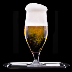 Frosty glass of light beer on black background