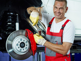 Car mechanic in a garage repairs a brake