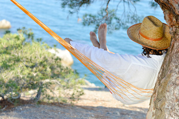 Man in hat in a hammock on pine tree in Crimea a summer day