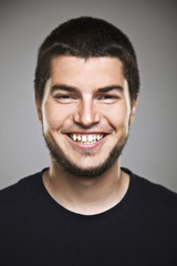 Portrait of a real smiling man over grey background.
