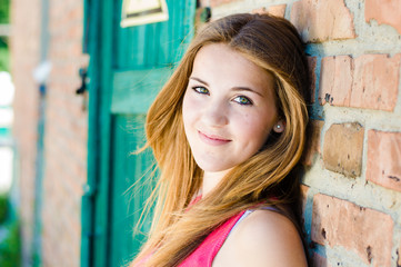 Fototapeta premium Young happy teenage girl standing at red brick wall background
