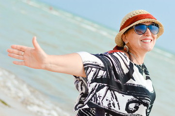 Happy mature woman enjoying breeze on seashore