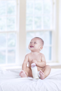 Happy baby with bottle at home - vertical
