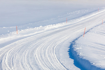Country road with red ploughing marks in the snow