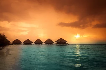 Selbstklebende Fototapeten Sunset on Maldives island, water villas resort © fotomaximum