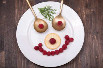 Fun food for kids - face on a plate of raspberries