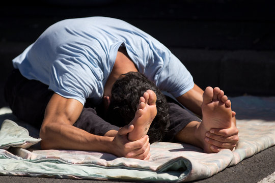 Jeune homme souple s'&eacute;tirant au sol.