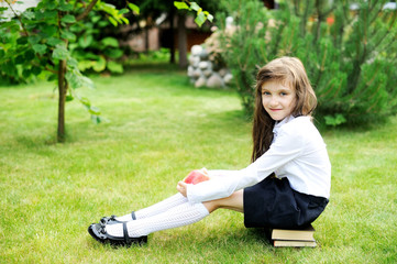 Young girl in school uniform sitting on books