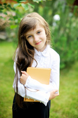 Fototapeta premium Young girl in school uniform holding a book