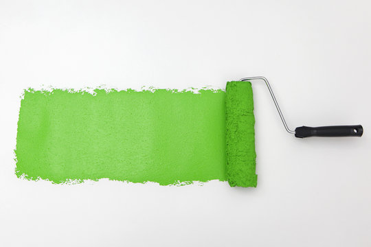 Green paint roller on white background