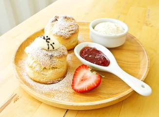 Scone spread with cream and strawberry jam